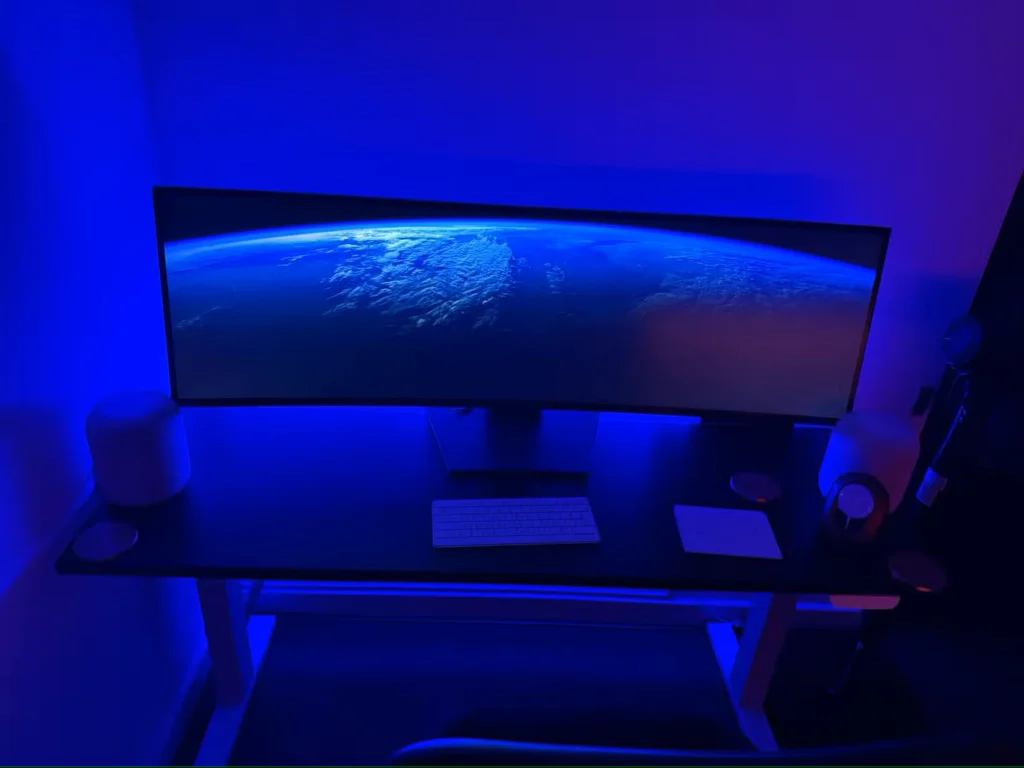 یک دفتر کار خانگی با یک چراغ نواری Philips Hue در پشت میز برای ظاهری مدرن و آبی رنگ.