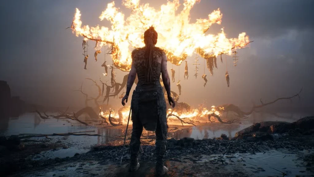 سنوا در Hellblade: Senua’s Sacrifice به درختی در حال سوختن نگاه می‌کند.