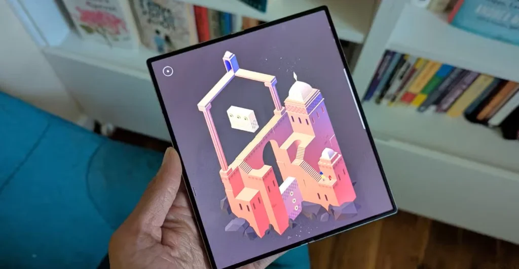 بازی Monument Valley 2 روی Galaxy Z Fold 6 با کتاب در پس‌زمینه.